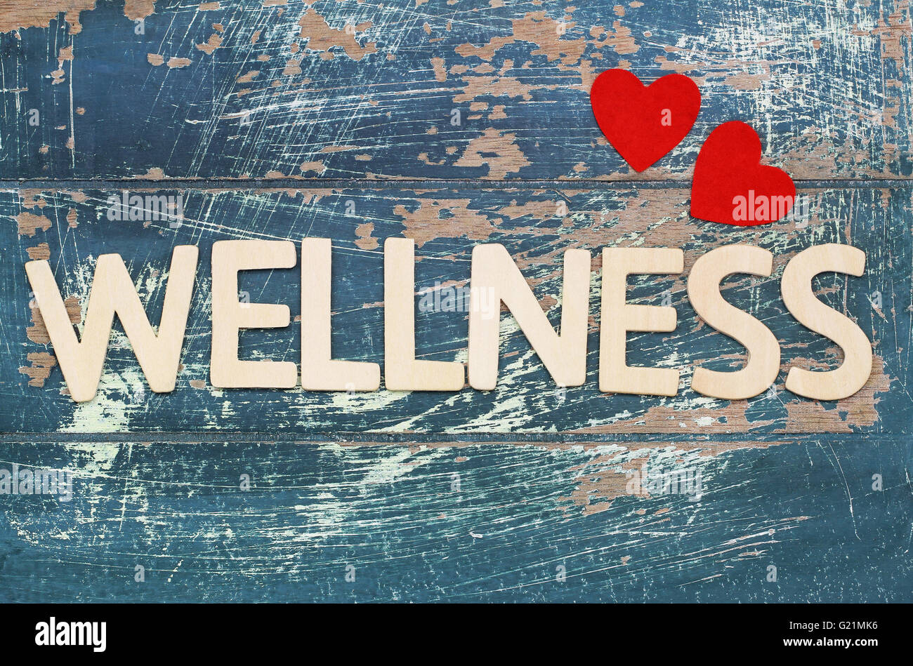 Wellness mit Holzbuchstaben auf rustikale Oberfläche und roten Herzen geschrieben Stockfoto