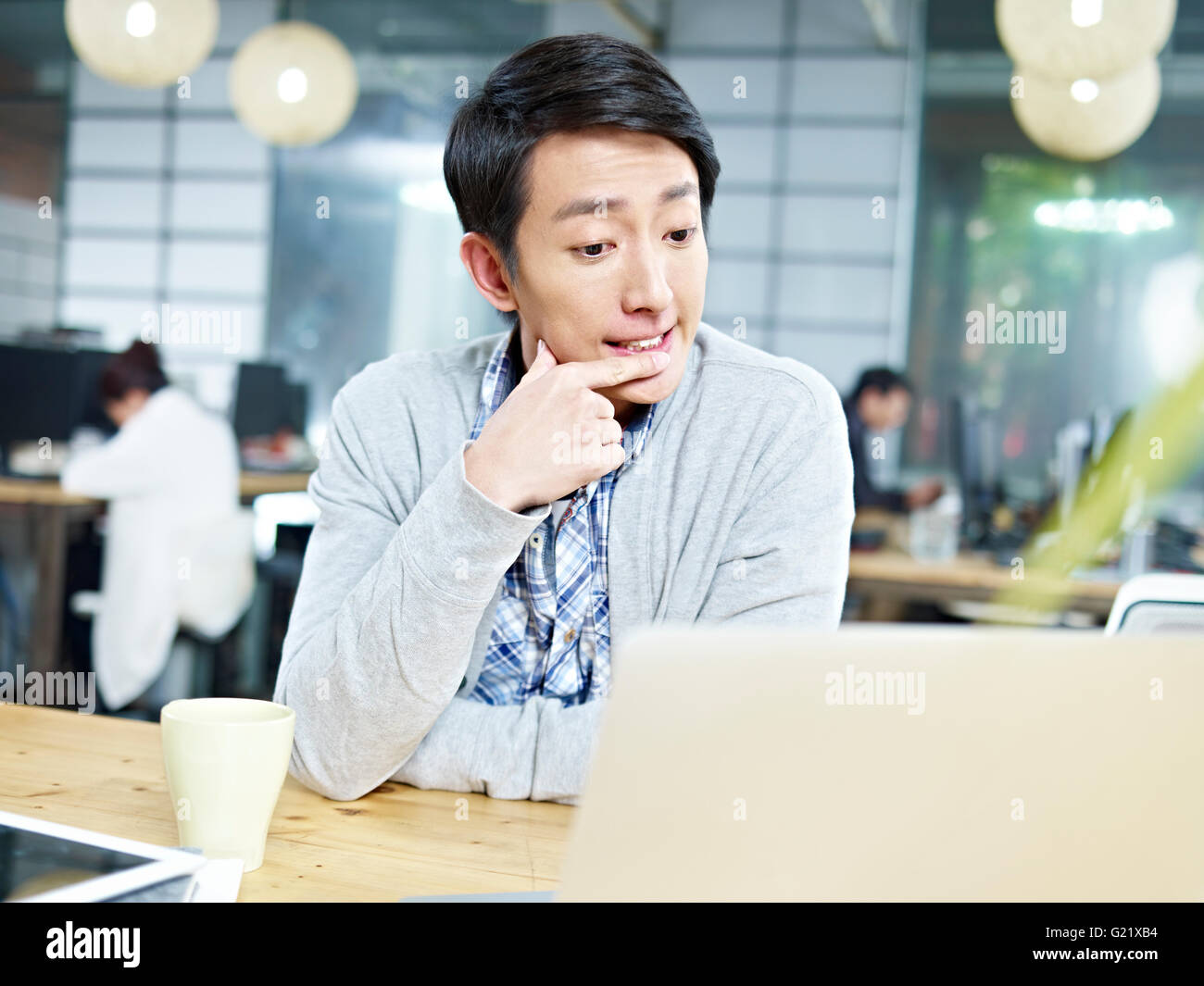 junge asiatische Unternehmer sitzen am Schreibtisch Denken schwer. Stockfoto