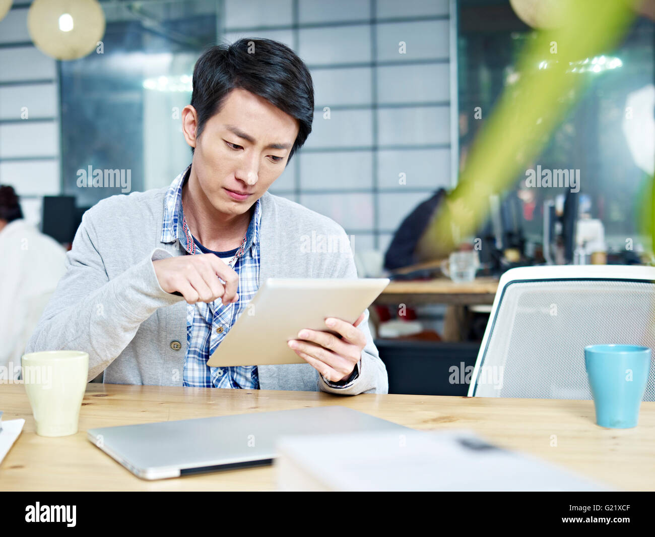junge asiatische Geschäftsmann, sitzen am Schreibtisch im Büro arbeiten mit Tablet-Computer. Stockfoto