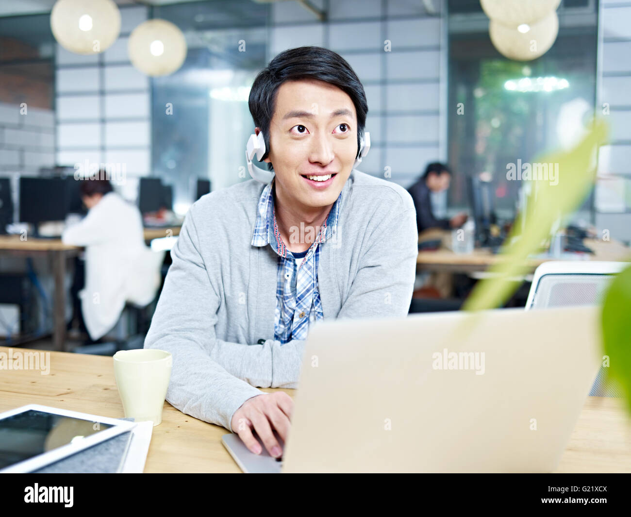 junge asiatische Geschäftsmann Musikhören während der Arbeit im Büro Stockfoto
