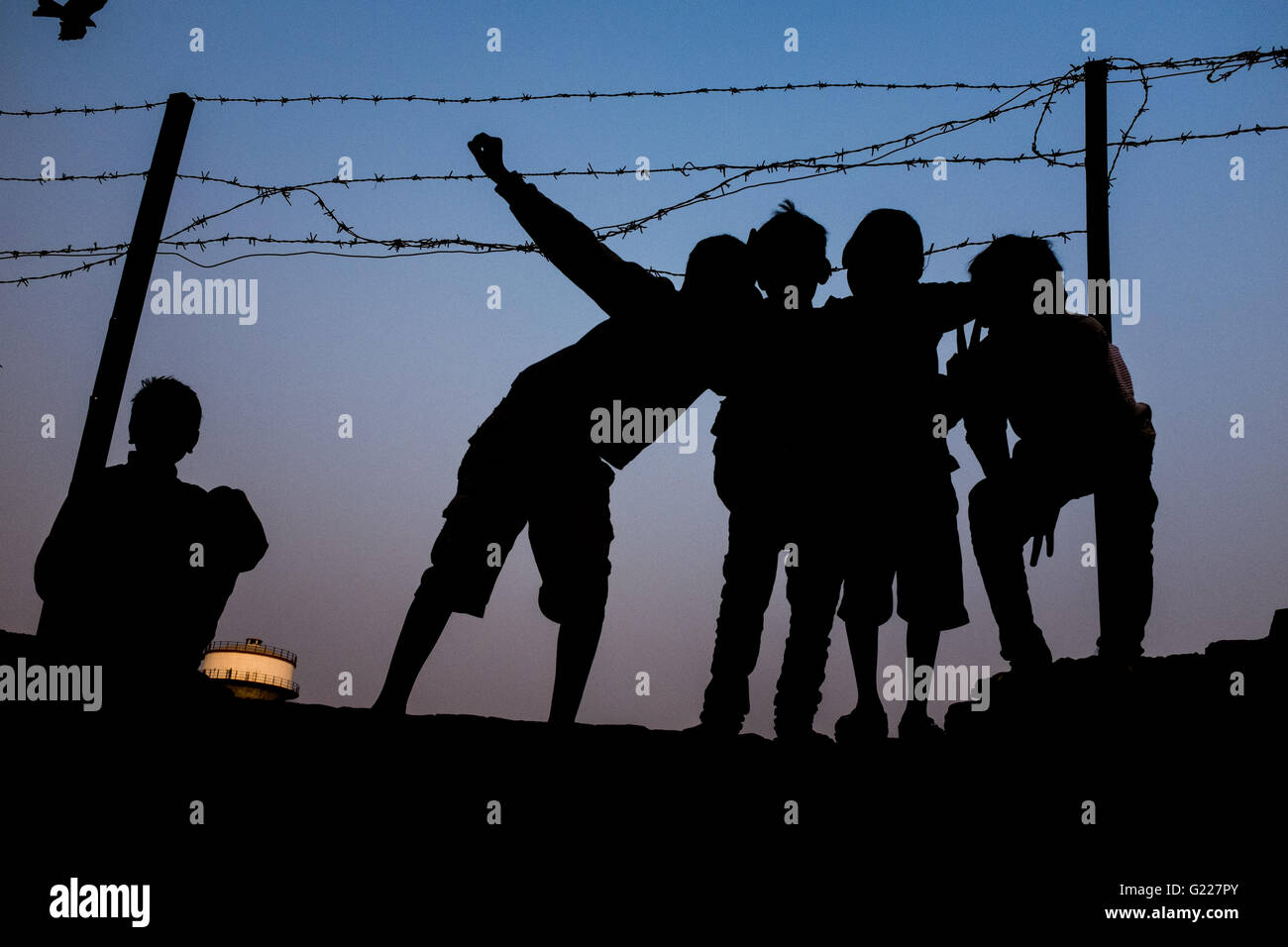 Silhouetten von Jungs spielen auf einer Wand in der Nähe von Stacheldraht, Delhi, Indien Stockfoto