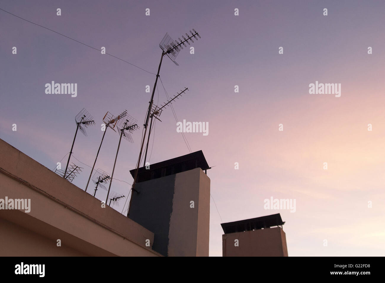 ein poetisches Bild von Fernsehantennen auf Dach mit rosa und blauen Wolkenhimmel bei Sonnenuntergang, Palma De Mallorca, Spanien, am Meer Stockfoto
