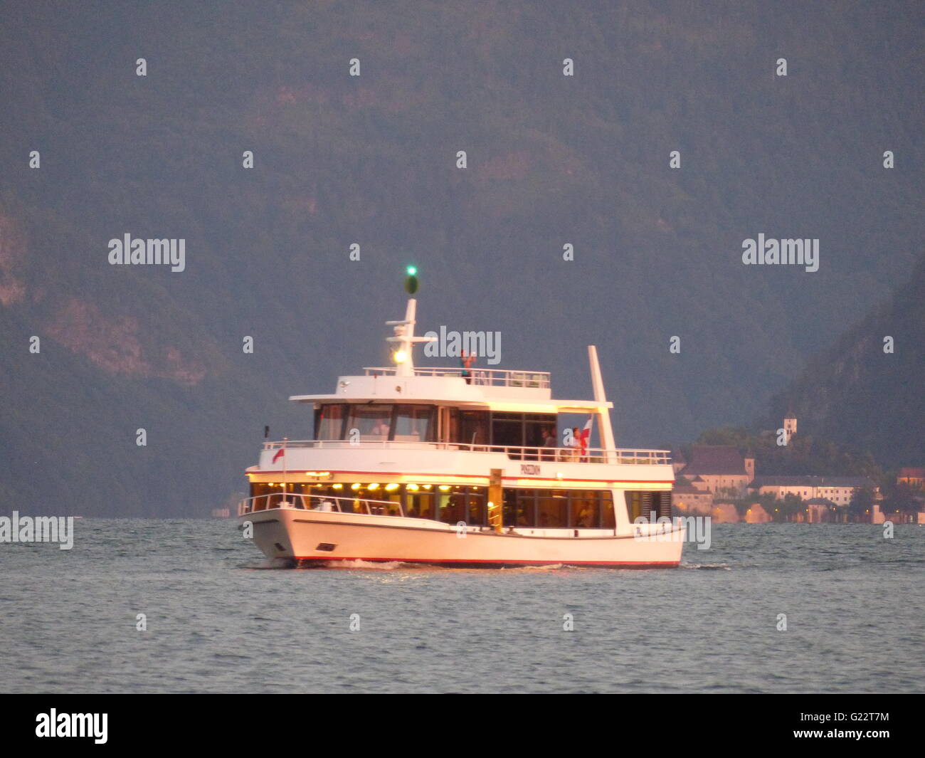 Österreich - Gmundner. Sightseeing-Schiff reist Poseidon, beleuchtet von Sonnenuntergang am See Traun zurück in den Hafen Stockfoto