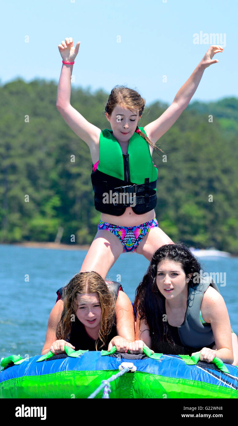 Drei Mädchen Schläuche hinter einem Boot auf einem See.  Man steht. Stockfoto
