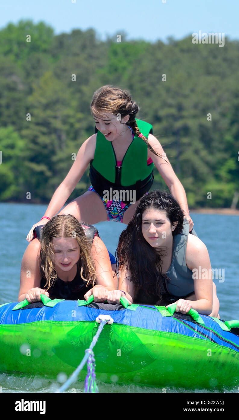 Drei junge Mädchen an einem Schlauch hinter einem Boot man tut einen Trick. Stockfoto