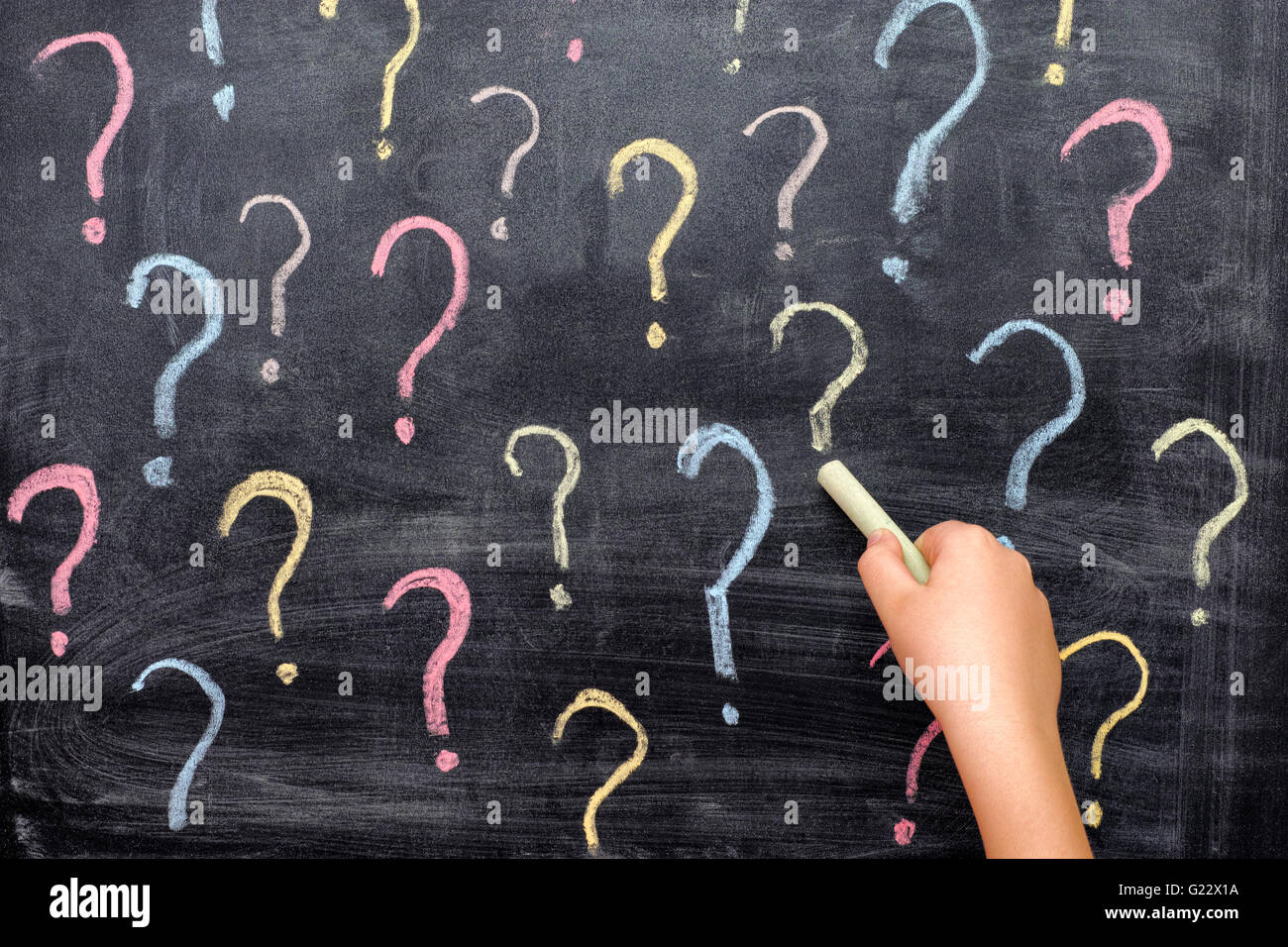 Kind zeichnen bunte Fragezeichen auf Tafel. Hautnah. Stockfoto