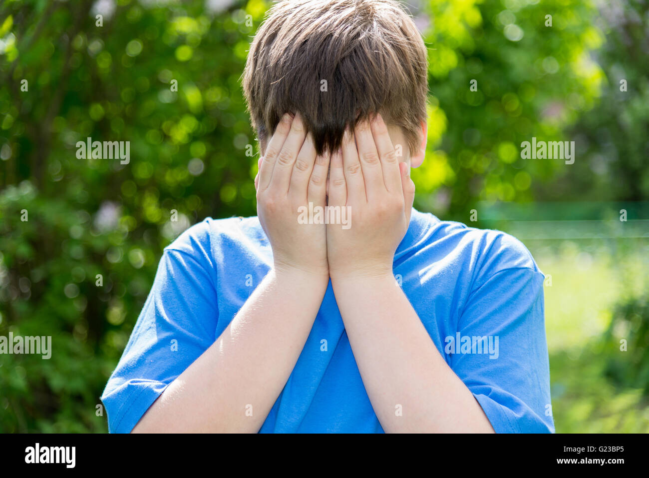 Teen Probleme - junge bedeckte sein Gesicht mit den Händen außerhalb Stockfoto