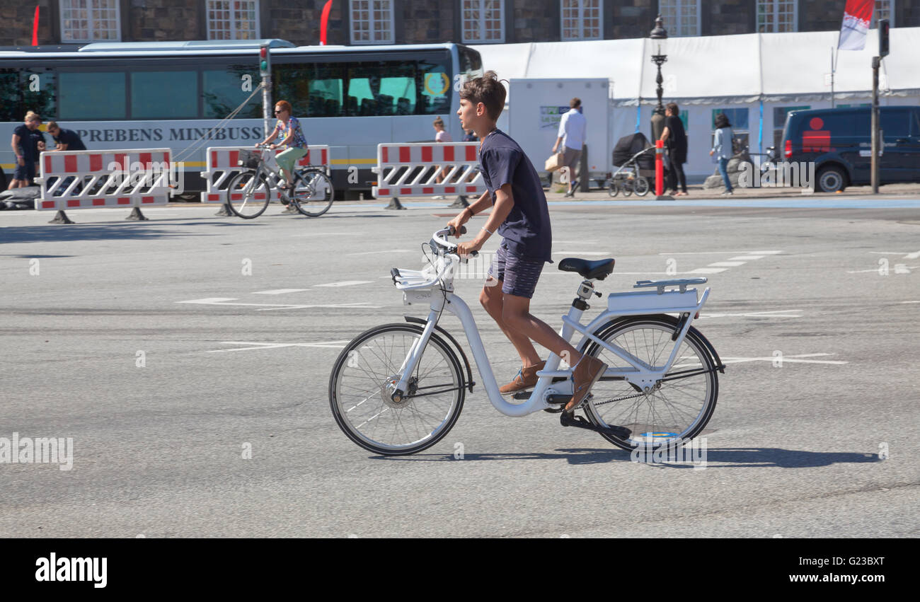 Ein Besuch junge in einem schnellen Start auf ein Gobike Elektromotor unterstützt Citybike in Copenhagen Straßen in Christiansborg. Kopenhagen, Dänemark. Stockfoto