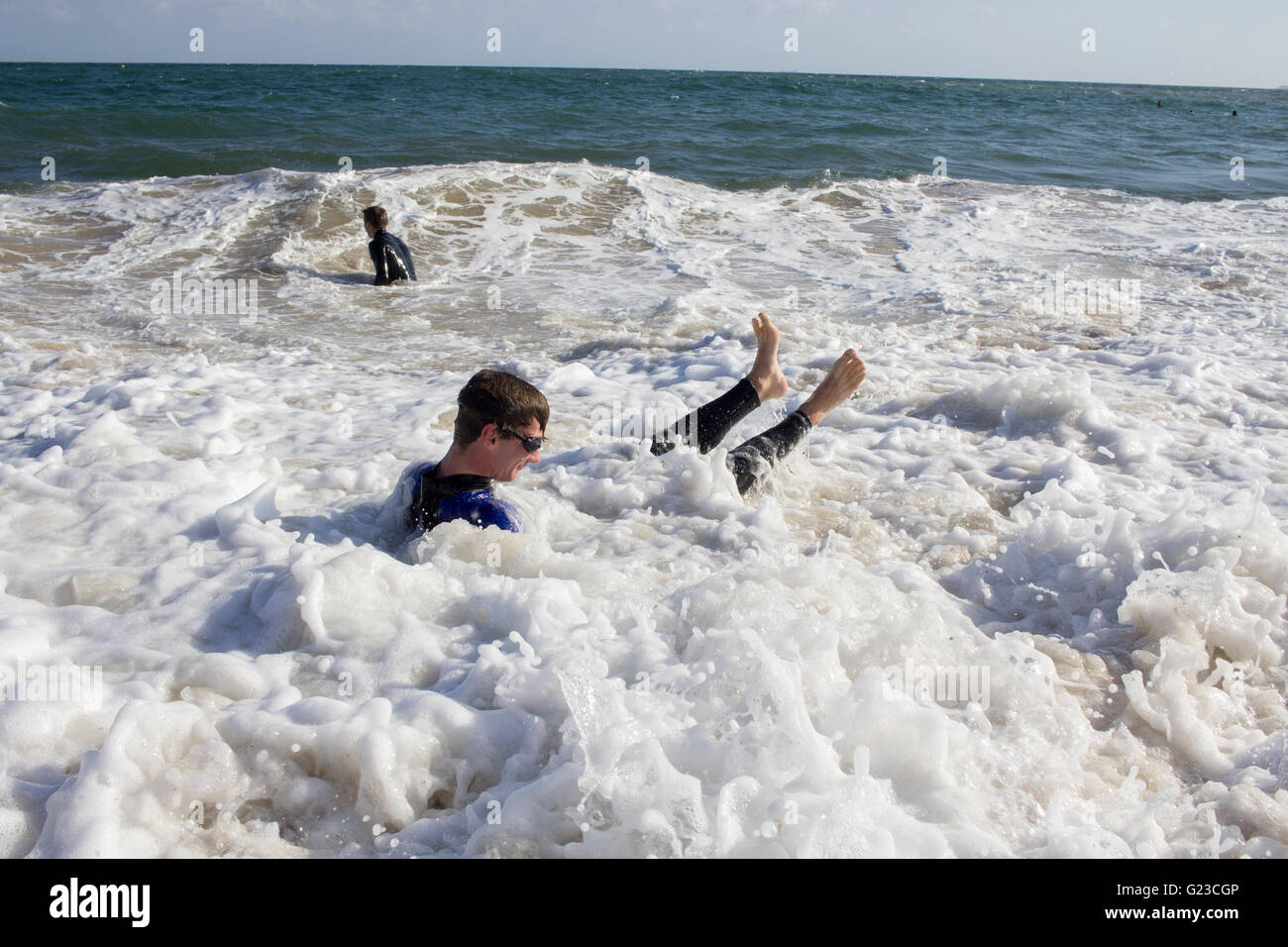 Zwei junge Männer spielen in der Brandung am Gyllyngvase Strand, Falmouth Stockfoto