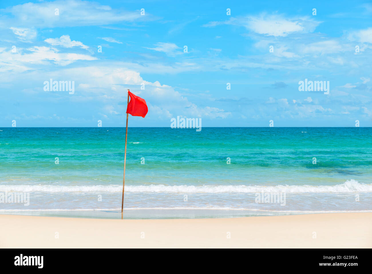 Rote Fahne am tropischen Strand und azurblaues Meer Stockfoto