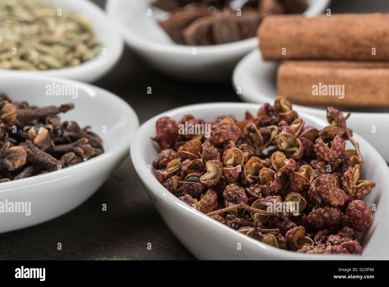 Szechuan-Pfefferkörner in weißen Löffel mit chinesischen fünf-Gewürze im Hintergrund Stockfoto