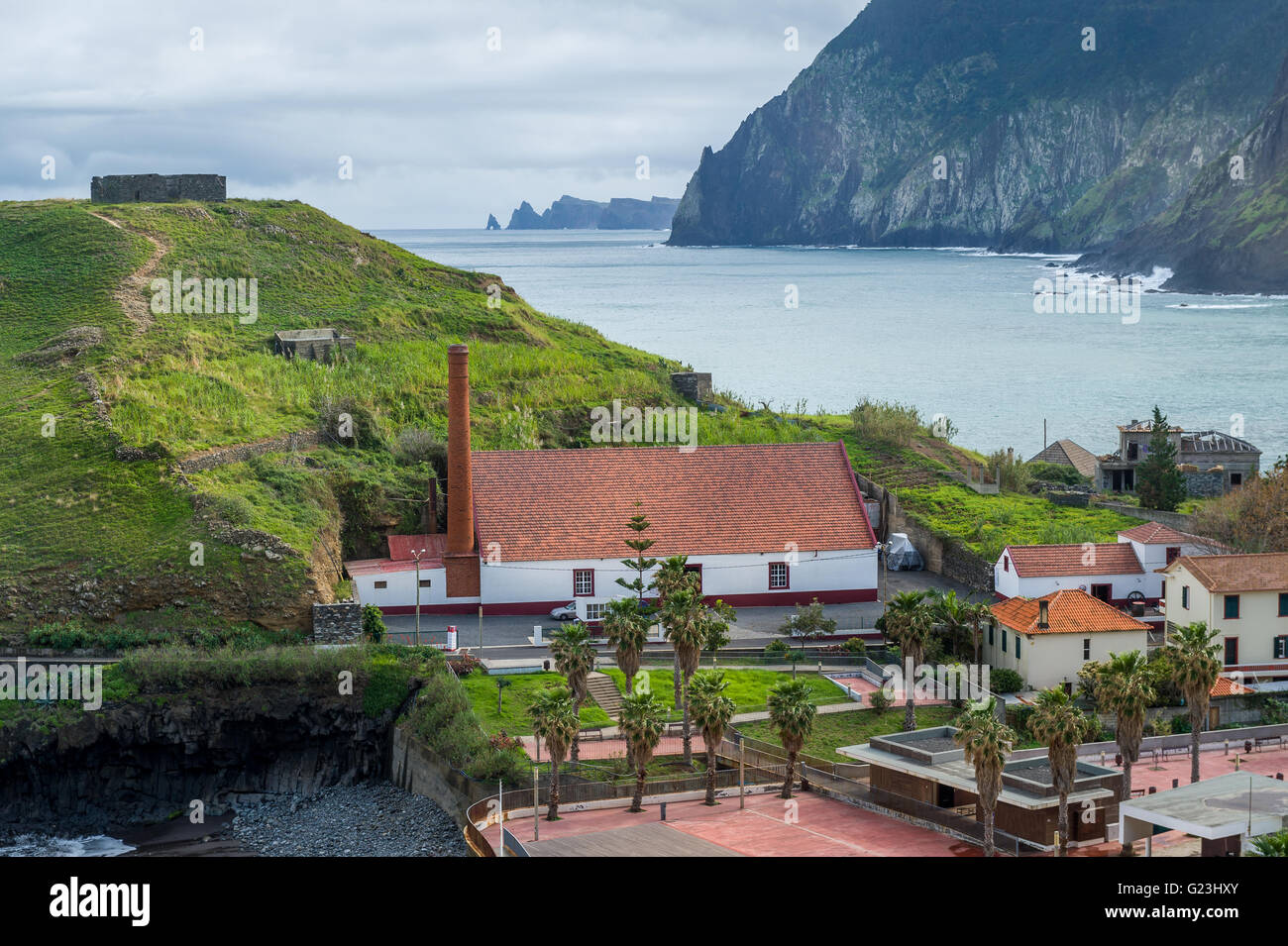 Blick auf die Stadt Porto da Cruz mit Festung Ruinen auf dem Hügel und Rumfabrik Stockfoto