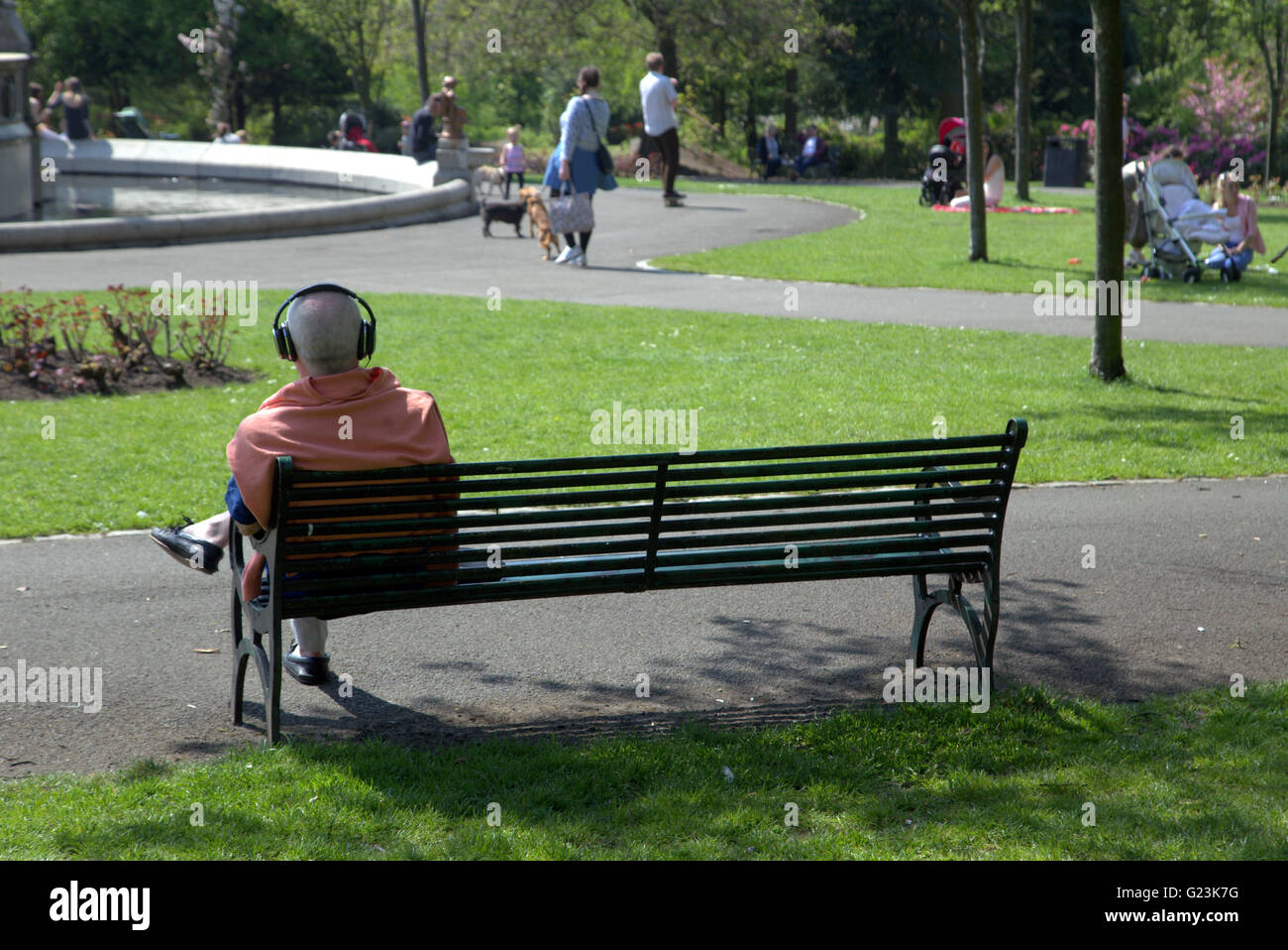 Mann oder junge mit Kopfhörern auf Park bench Kelvingrove Park Glasgow, Scotland, UK. Stockfoto