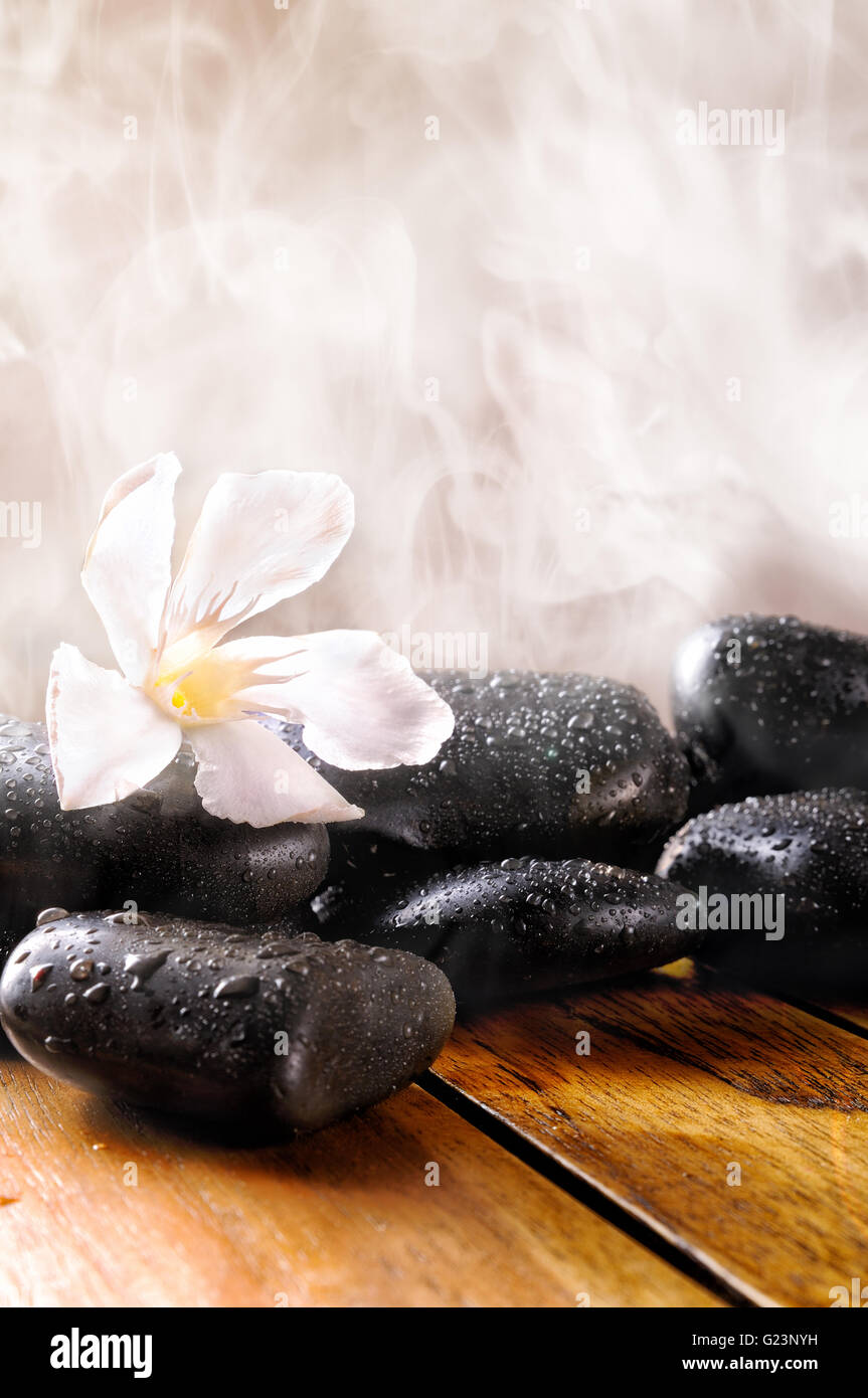 Gruppe von schwarzen Steinen auf Holz-Basis, Dampf-Hintergrund. Sauna, Therapie, Entspannung und Gesundheit Konzept. Vertikale Zusammensetzung. Stockfoto