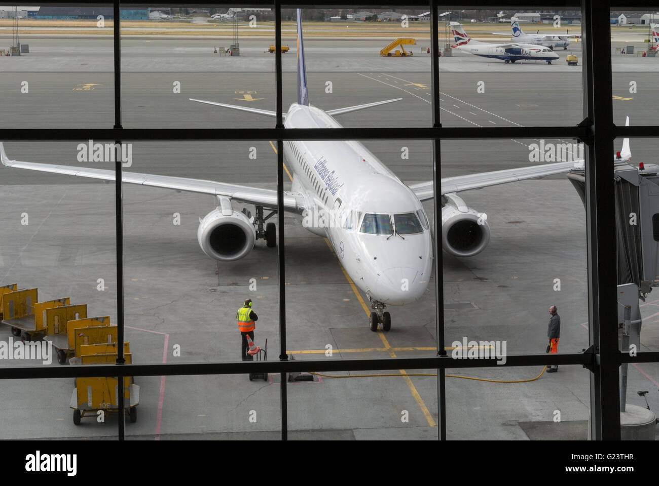 Lufthansa Flug von Frankfurt, Ankunft am Flughafen Billund, Dänemark. Embraer Jets in der Abfahrt Bereichsfenster gerahmt. Stockfoto