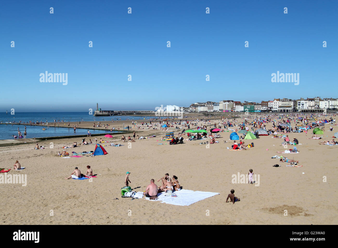 Menschen genießen den Sonnenschein an einem sonnigen Tag am Strand von Margate in East Sussex, England Stockfoto