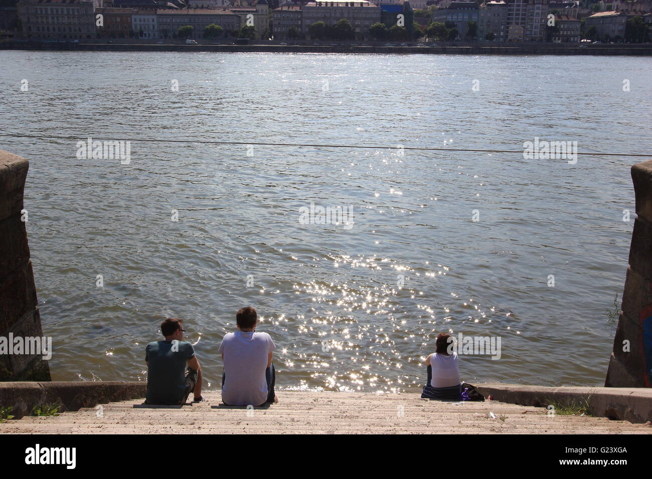 Männer und Frauen sitzen vom Ufer Donau, Budapest, Ungarn Stockfoto