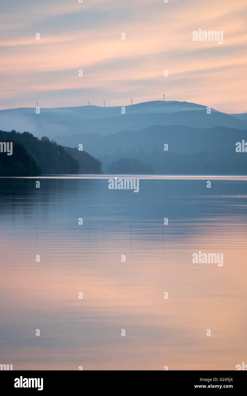 Sonnenuntergang über Coniston Water mit Windkraftanlagen auf Kirkby Moor in der Ferne, Cumbria. Stockfoto