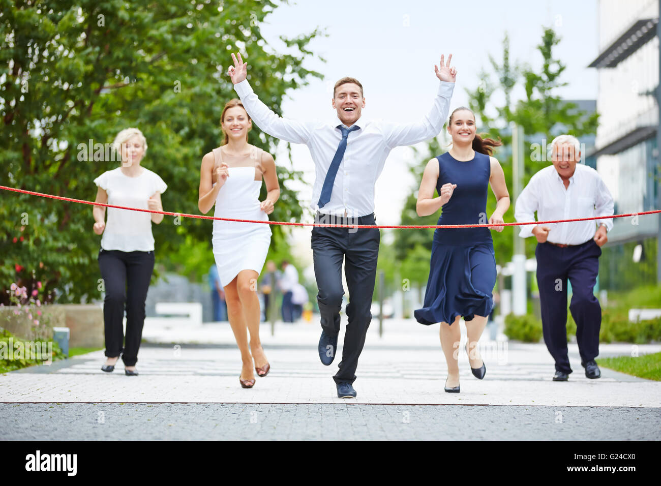 Business-Mann ist der Gewinner beim laufen mit einem Business-Team bis zur Ziellinie Stockfoto