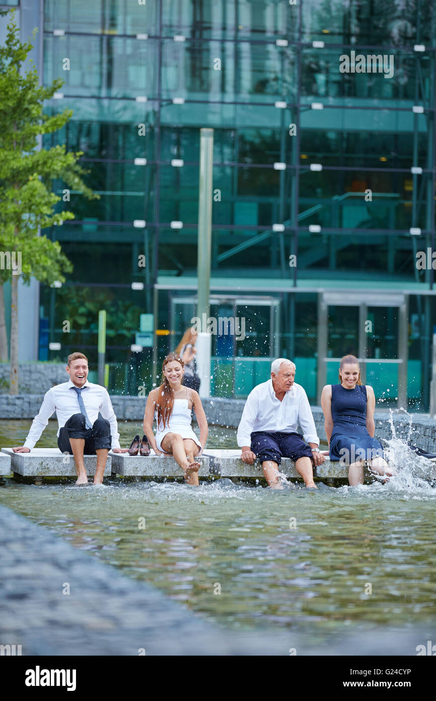 Business-Team Spritzwasser im Sommer mit ihren Füßen in einem See Stockfoto