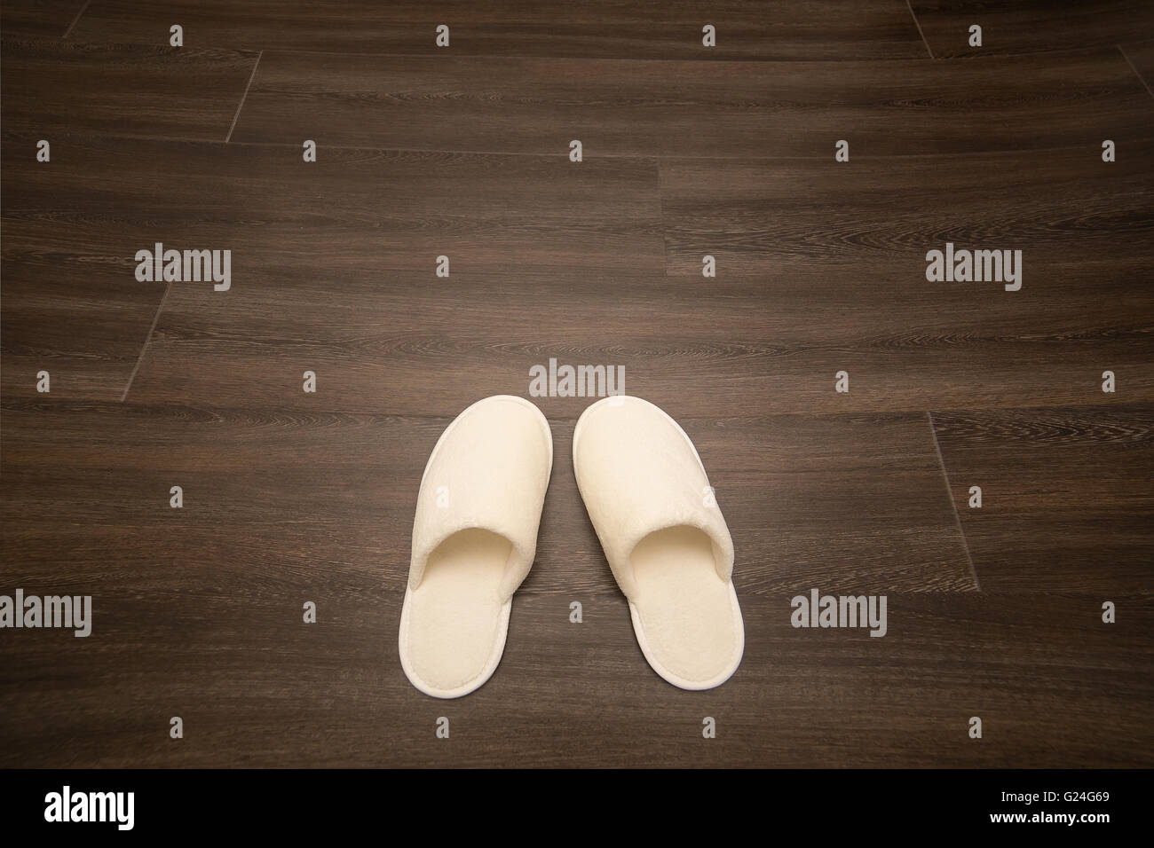 weiße weiche Hausschuhe stehen auf Holzboden Stockfoto