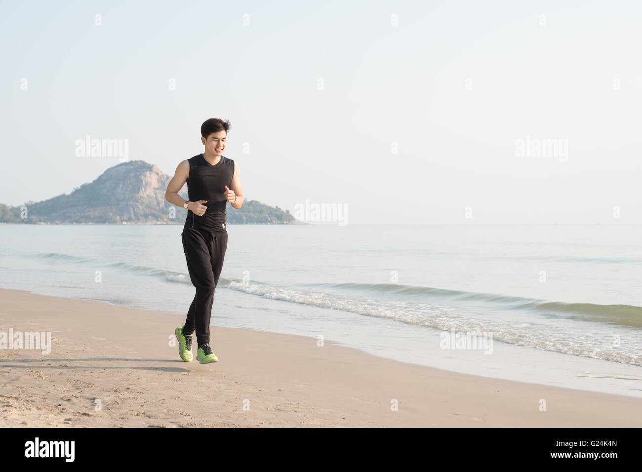 Asiatische junge Mann läuft allein am Strand morgens Stockfoto
