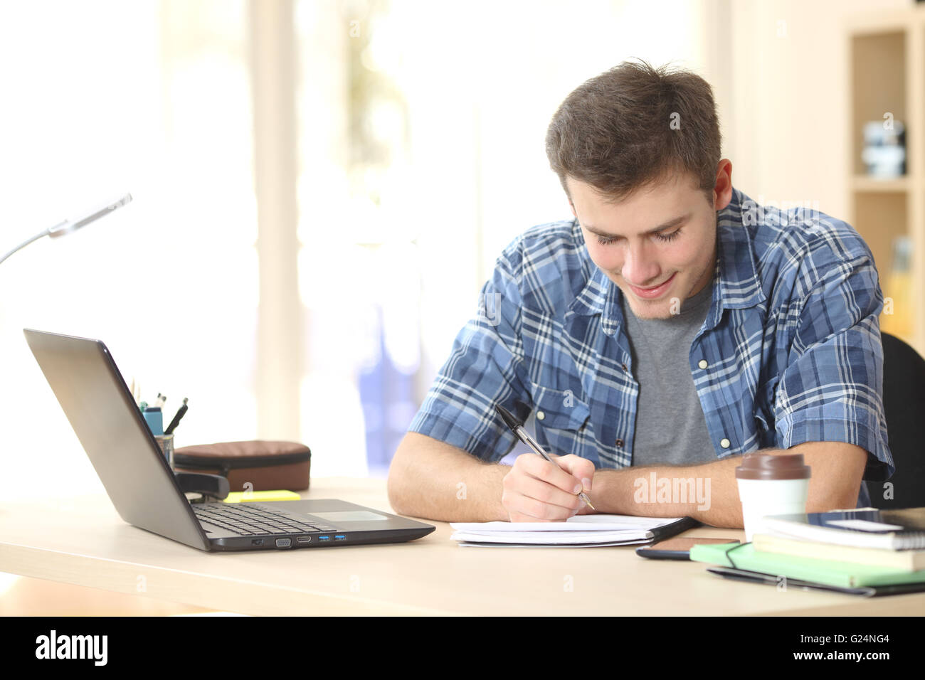 Student studieren und Schreiben von Notizen in einem Notizbuch sitzen an einem Schreibtisch zu Hause Stockfoto