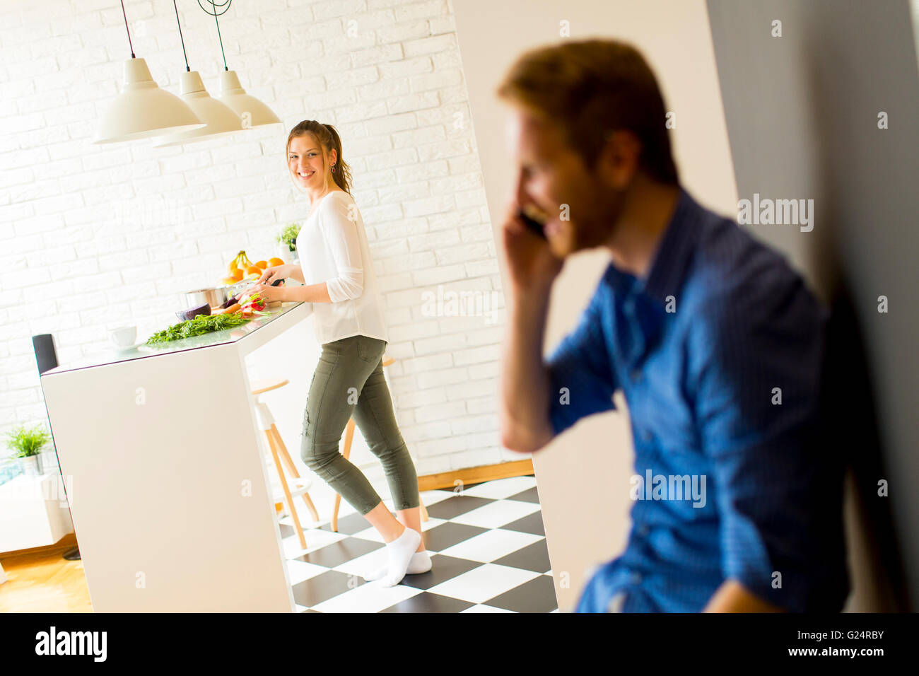 Mann am Telefon in der Küche mit Frau Kochen Stockfoto