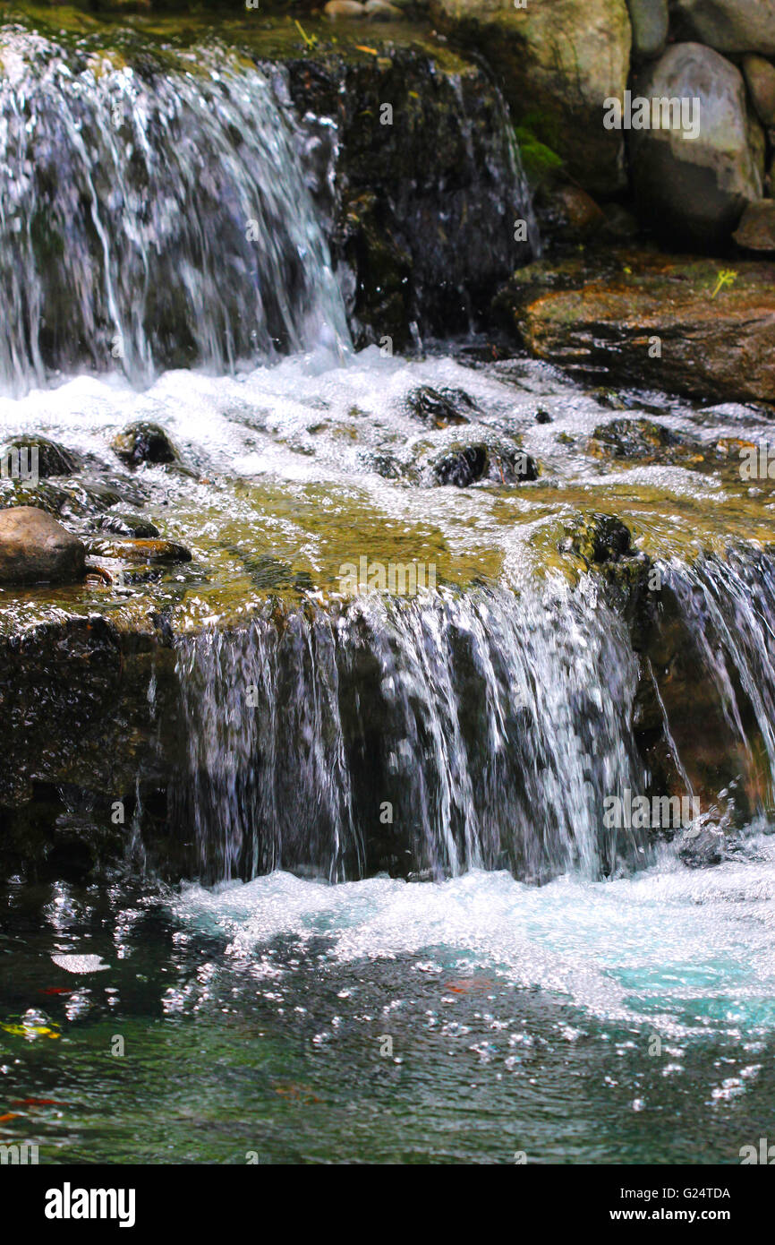 Ein Gartenteich unterstützt Multi-tiered Wasserfall mit vielen Schichten der Felsplatten. Stockfoto