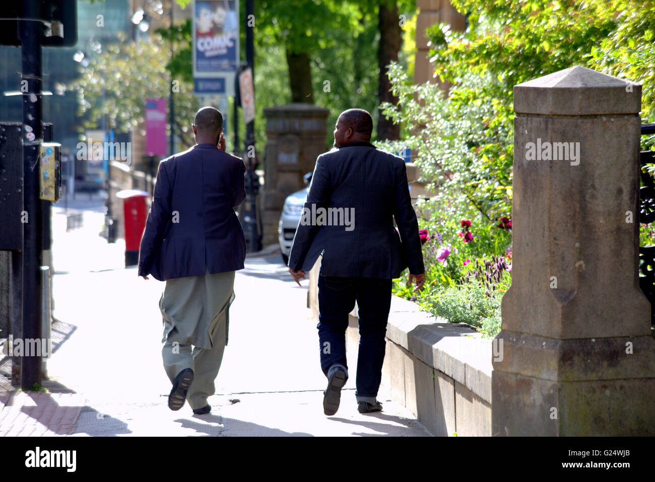 Zwei schwarze muslimische Männer zu Fuß auf der Straße sprechen Glasgow, Scotland, UK. Stockfoto