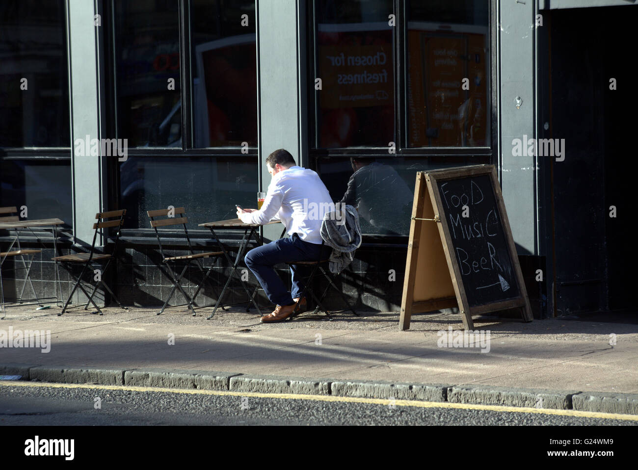 Mann einen Drink auf seine eigene mit Handy Finnieston, Glasgow, Scotland, UK. Stockfoto