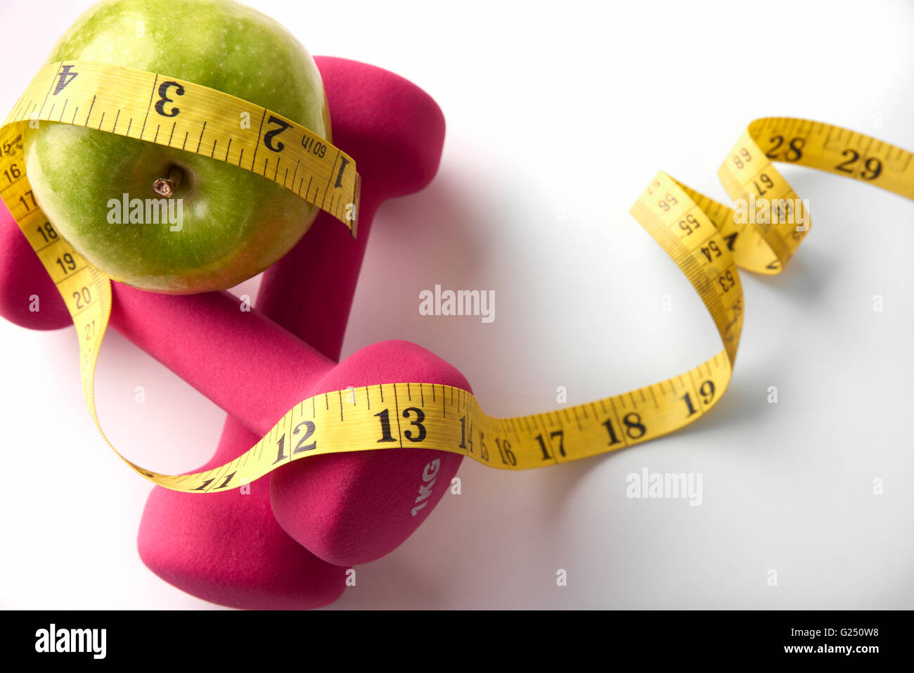 Rosa Hanteln mit Apfel und Maßband. Konzept-Gesundheit, Ernährung und Sport. Horizontale Komposition. Ansicht von oben Stockfoto