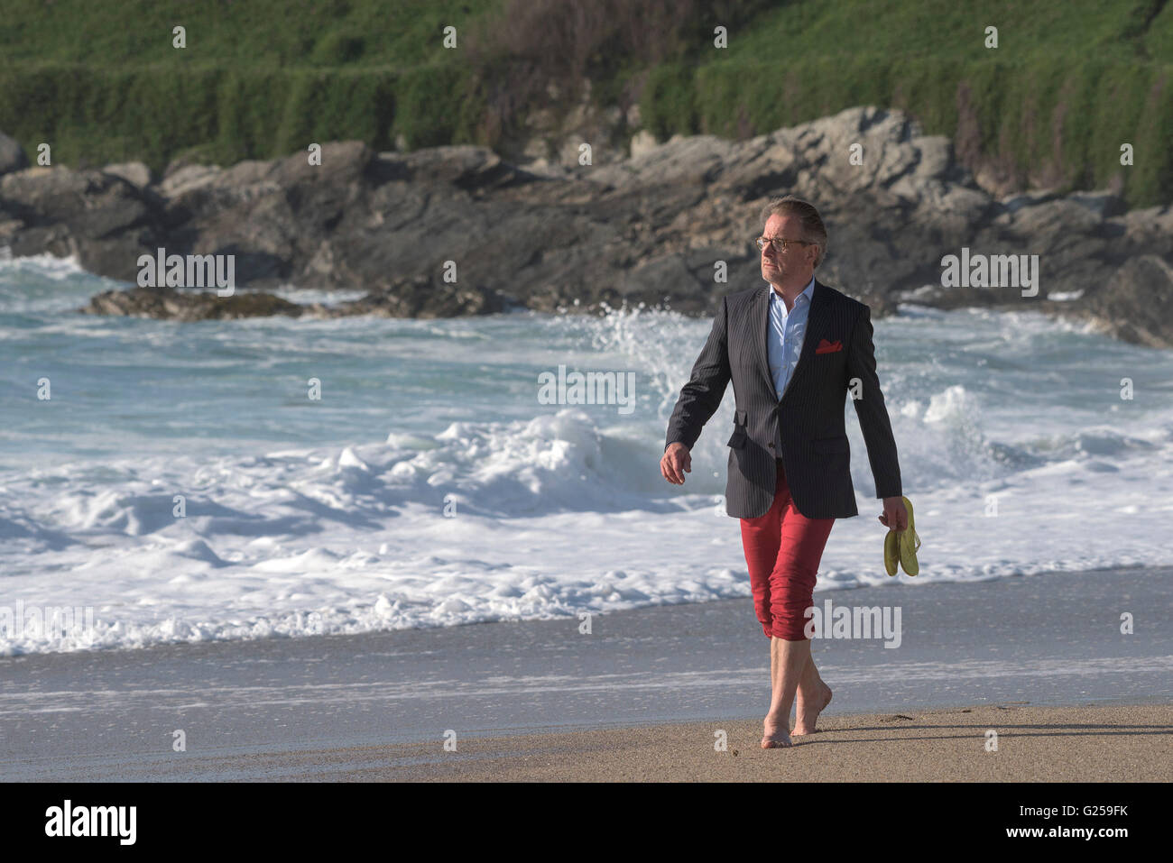 Ein elegant gekleideter Mann nimmt ein Abend Fistral Strand in Newquay, Cornwall entlang schlendert. Stockfoto
