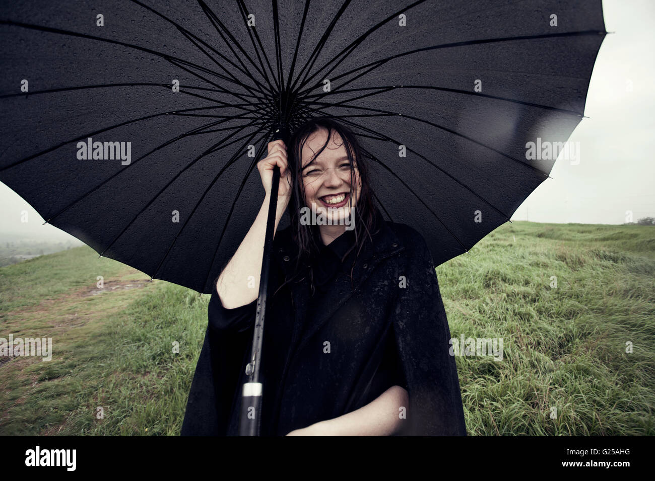 Porträt von lächelnden Frau Holding Regenschirm im wind Stockfoto