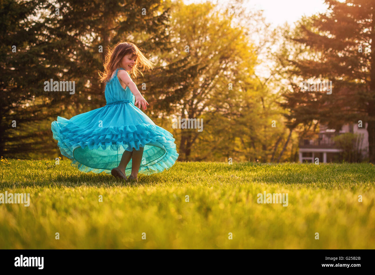 Mädchen im Garten drehen in einem Kleid Stockfoto