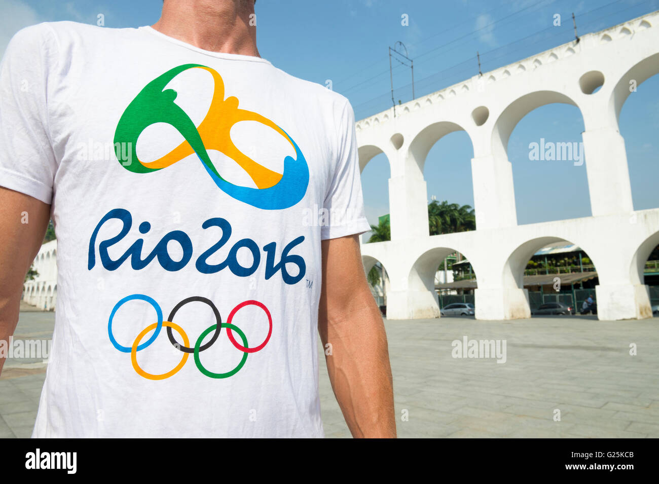 RIO DE JANEIRO - 29. März 2016: Mann mit offiziellen Olympischen Spiele 2016 in Rio Souvenir T-shirt steht die Arcos da Lapa Bögen. Stockfoto