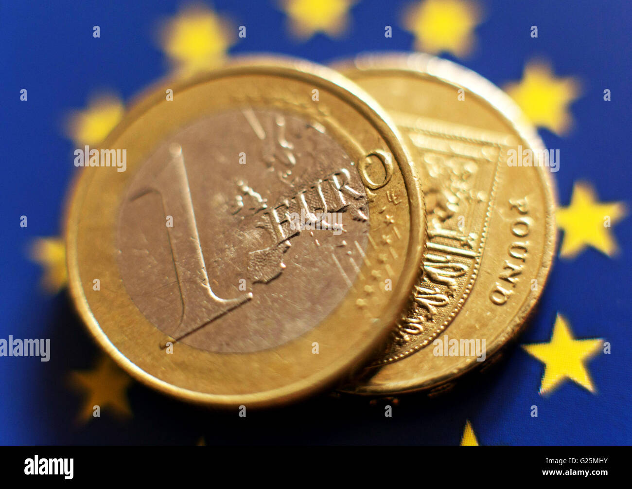 Eine 1-Euro-Münze und eine demjenigen Pfund-Münze auf dem Hintergrund der europäischen Flagge in London. Stockfoto