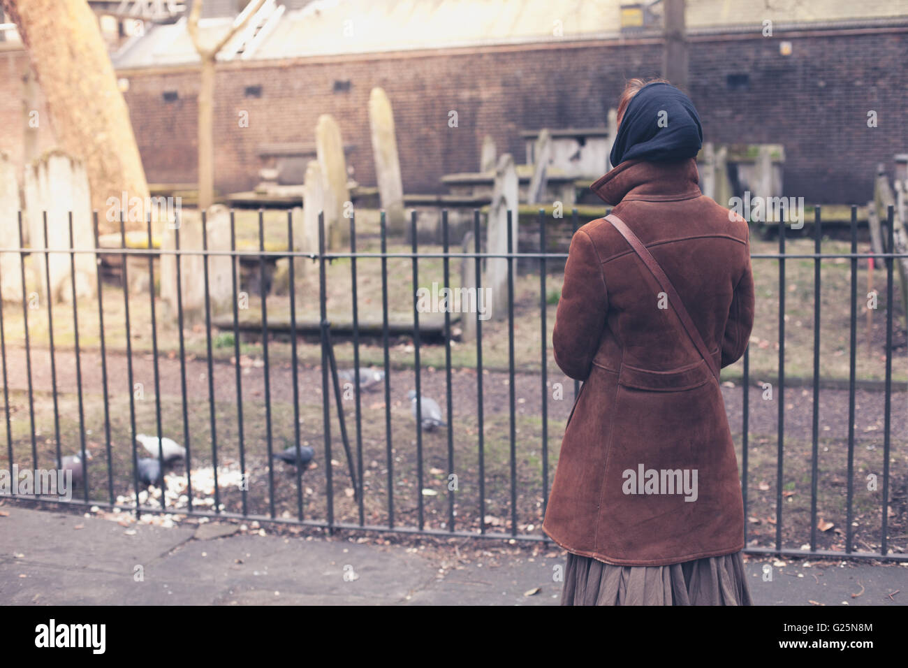 Eine Frau füttert einige Tauben auf einem Friedhof Stockfoto