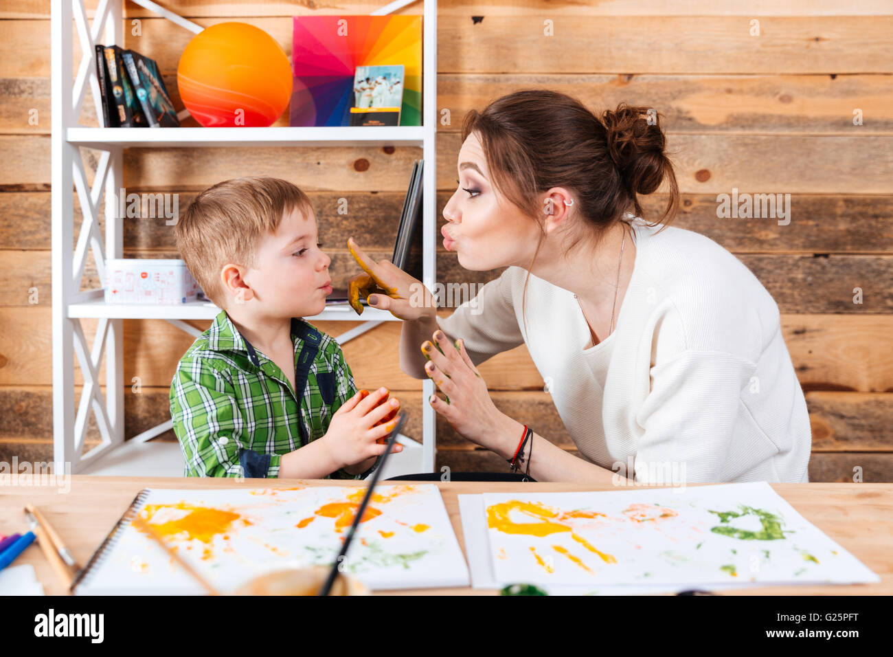 Glückliche Mutter berühren Gesicht ihres kleinen Sohnes mit Händen in bunten Farben bemalt und gemeinsam Spaß haben Stockfoto
