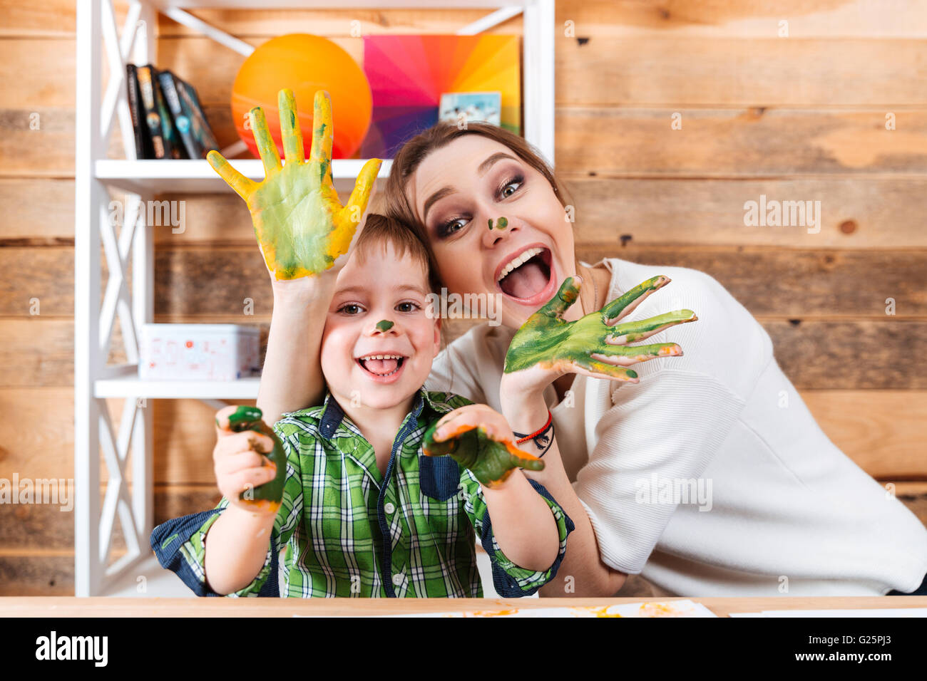 Fröhlich aufgeregt Mutter und kleinen Sohn mit bemalten Händen in bunten Farben, die gemeinsam Spaß haben Stockfoto