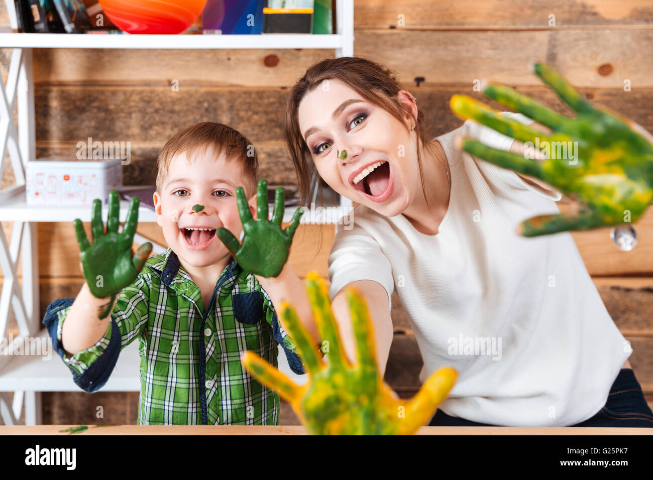 Lächelnd aufgeregt, kleinen Jungen und seiner Mutter zeigt Hände in bunten Farben bemalt und lachen Stockfoto