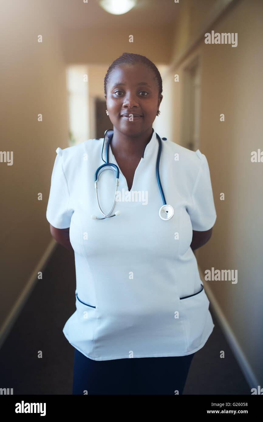 Porträt von glücklich afrikanischen Krankenschwester im Flur stehen. Positive und fürsorgliche Ärztin mit Stethoskop. Stockfoto