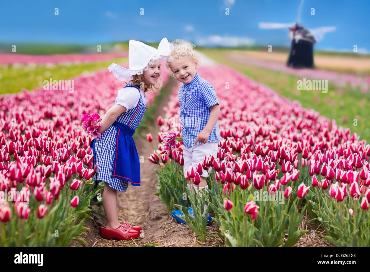 Glücklich niederländische Kinder spielen im blühenden Blumen Tulpenfeld.  Jungen und Mädchen in traditioneller Tracht Stockfoto