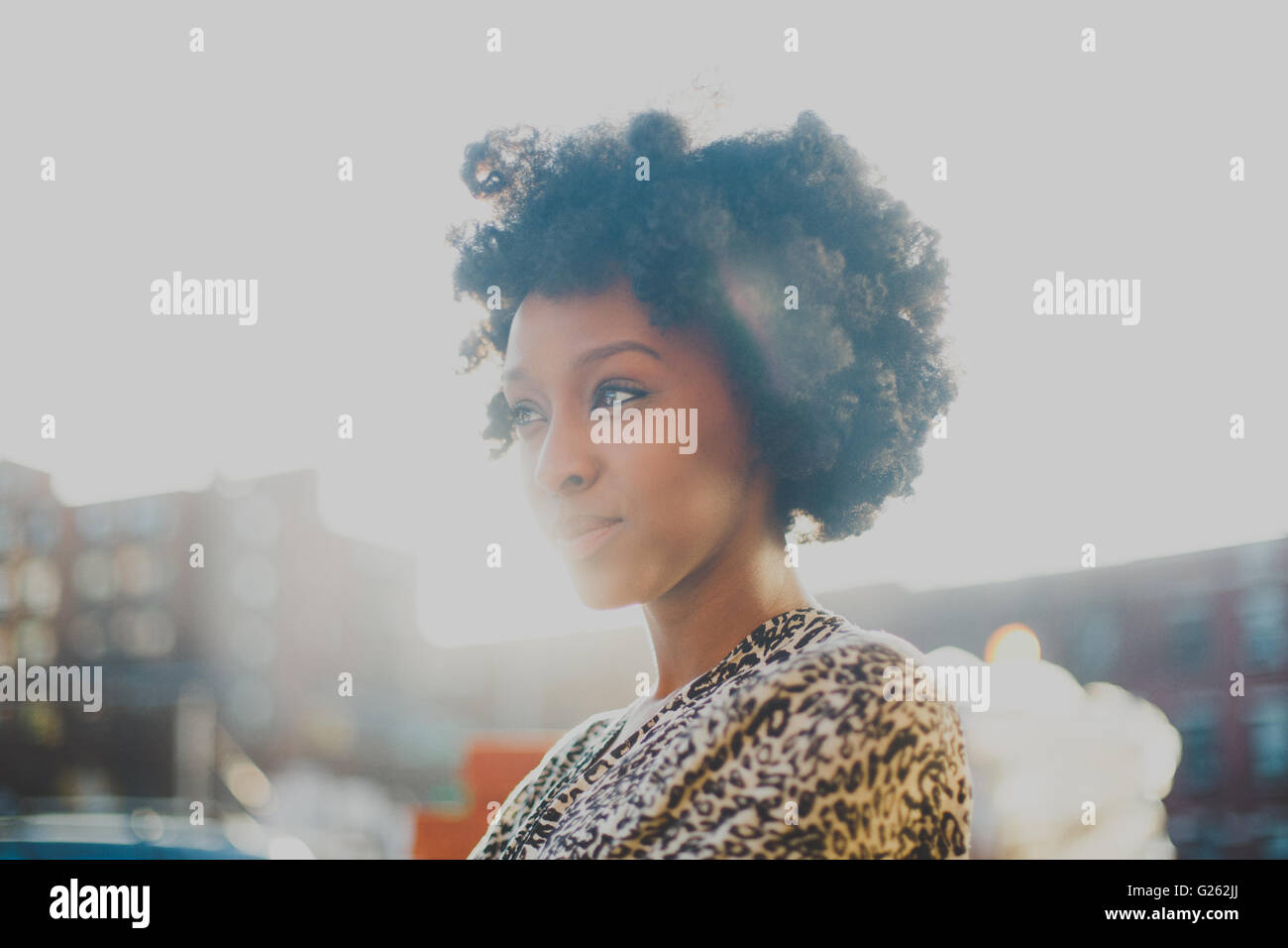 Junge Frau mit Afro lächelnd im städtischen Umfeld Stockfoto