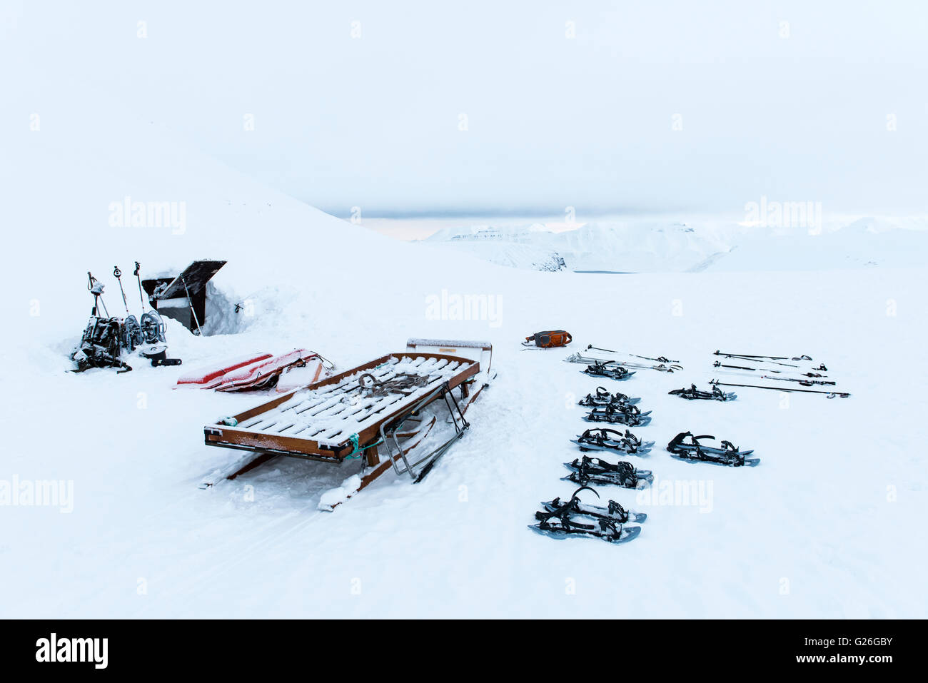 Ski-Ausrüstung am Eingang der Eishöhle mit schneebedeckten Bergen Longyearbyen, Svalbard, Spitzbergen, Norwegen Stockfoto