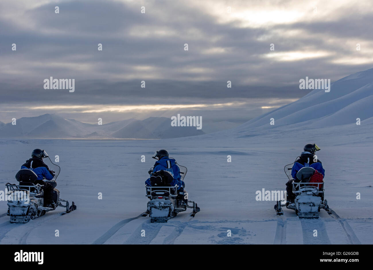 Motorschlitten mit schneebedeckten Bergen Longyearbyen bei Dämmerung, Svalbard, Spitzbergen, Norwegen Stockfoto