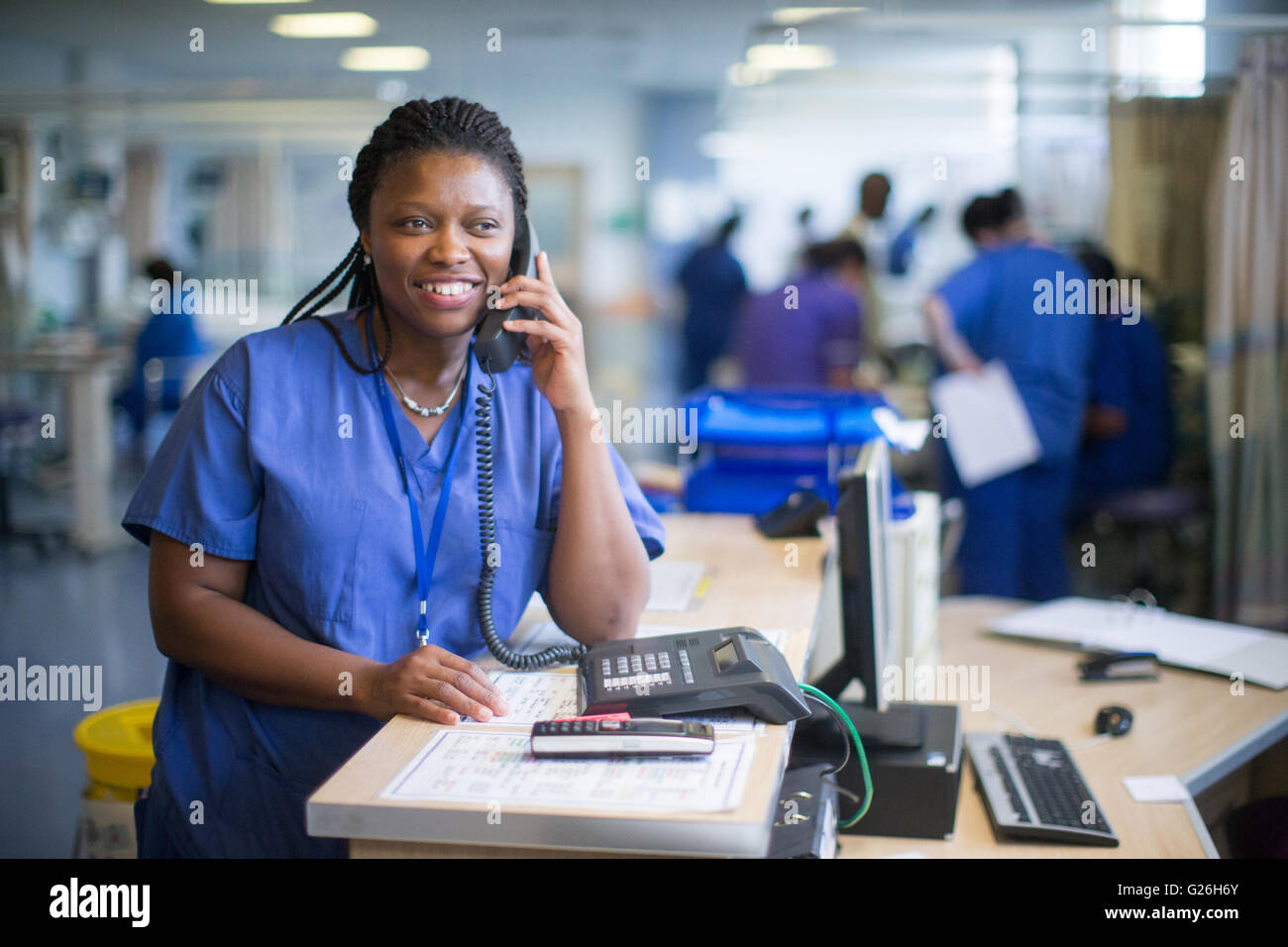 Krankenschwester an einer Workstation in einer Gemeinde, die Beantwortung von Anfragen und medizinische Unterlagen Stockfoto