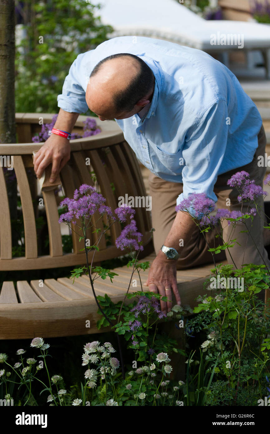 Chelsea Flower Show, London, UK. Mann, eine Gartenbank auf seinem Display abschleifen. Stockfoto