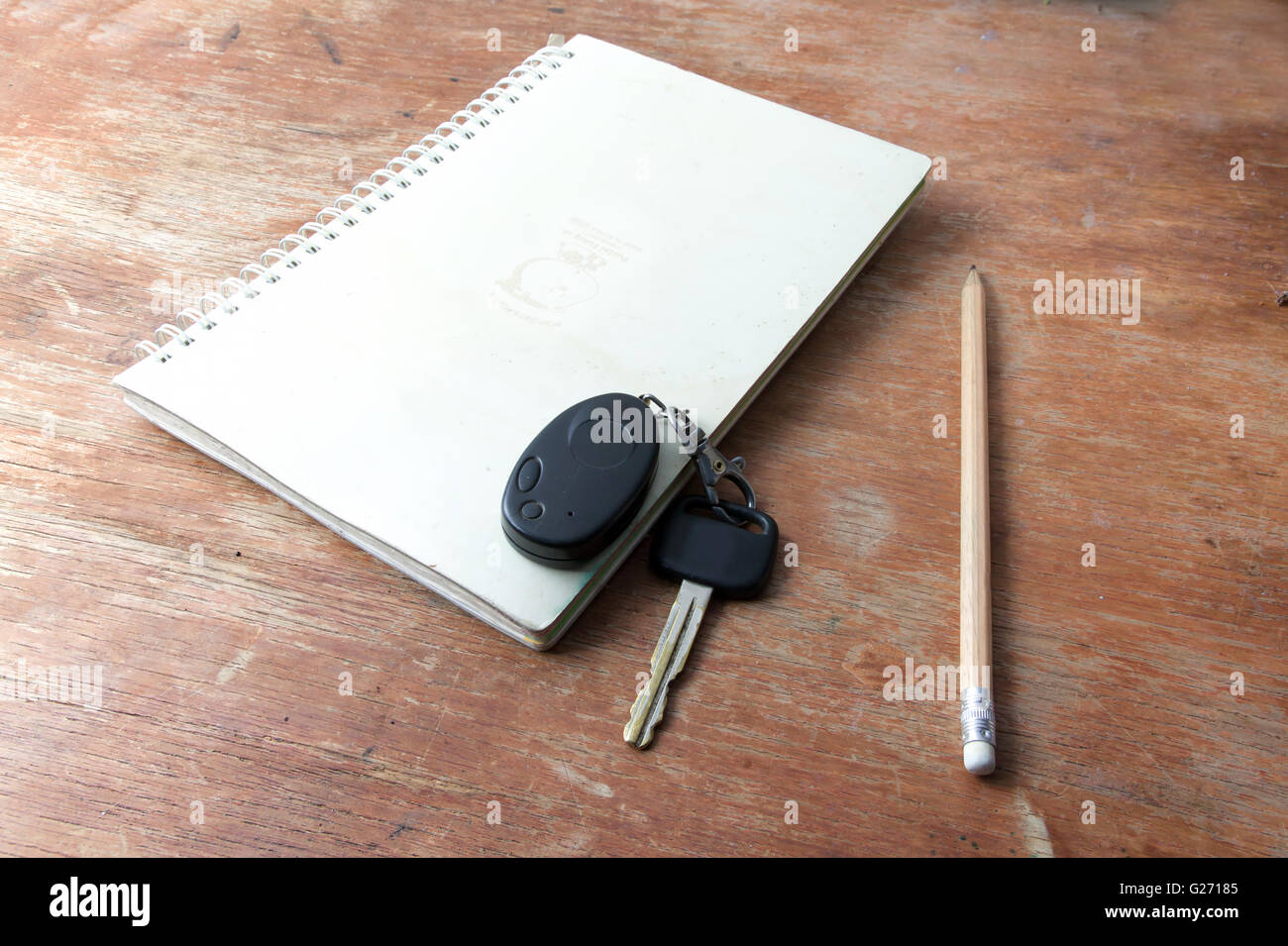 Buch-Hinweis und Bleistift und Schlüssel auf dem alten Holztisch. und remote-Alarm Auto. Stockfoto