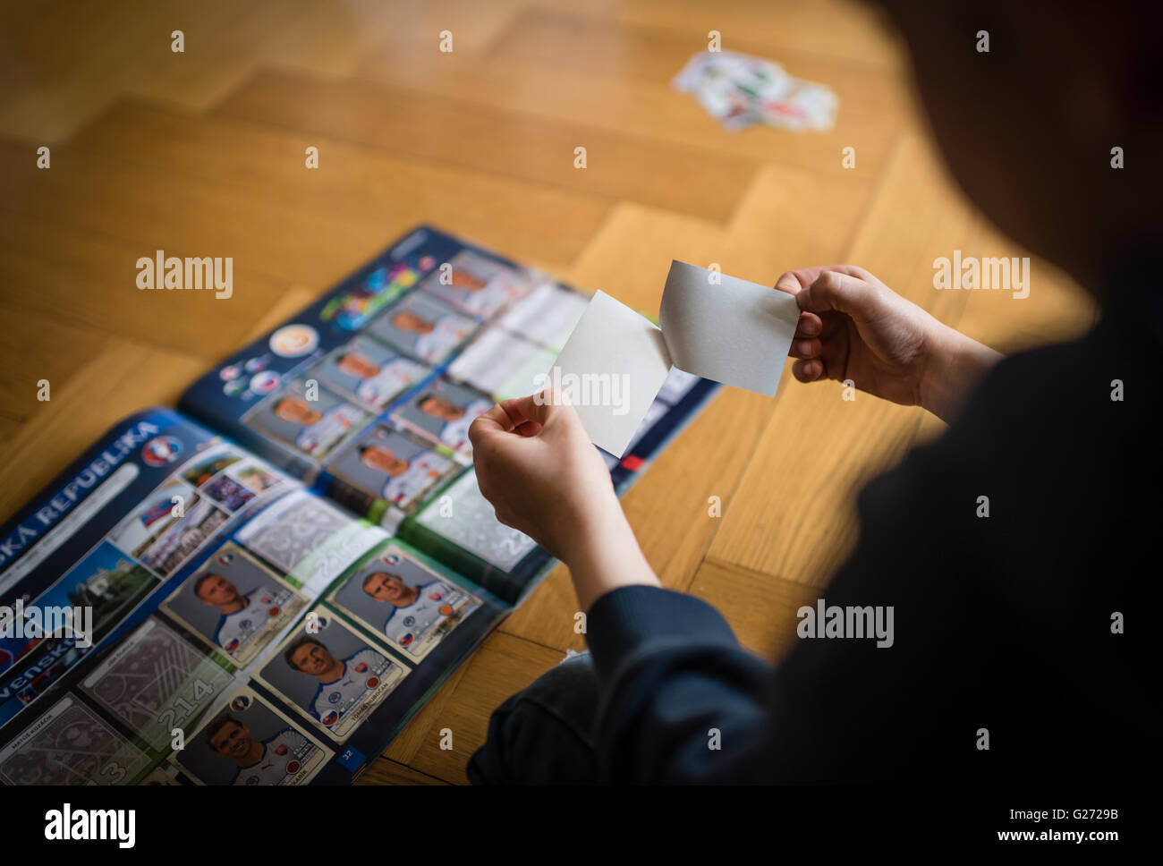 Ein 8 Jahre alter Junge ist Fußball-Sammelkarten in seinem Aufkleber Sammlung Sammelalbum einfügen. Stockfoto